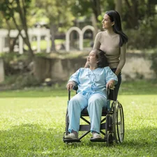 A woman in a wheelchair standing next to a man in a park related to Elevating Care: The Comfort and Convenience of Invacare Hospital Beds