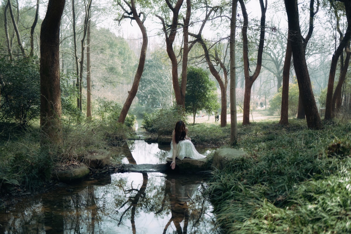 a woman in a white dress sitting on a rock in a forest related to Discover the Tranquil Charm of Blisswood Bed and Breakfast
