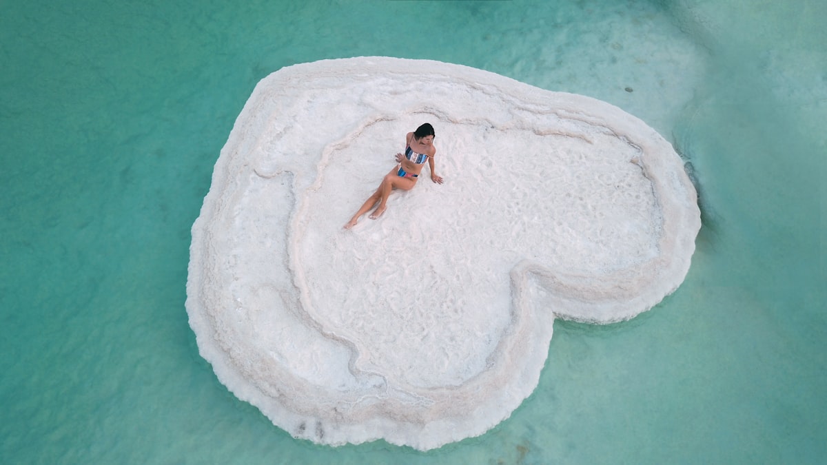 a woman is sitting on a rock in the water related to A Heart Shaped Bed: The Ultimate Symbol of Romance