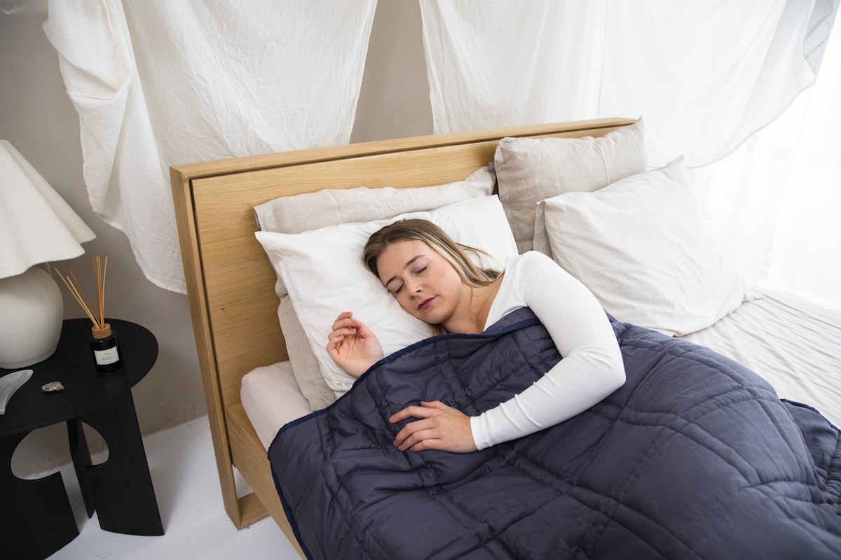 a woman laying in bed with a blue comforter related to Navy Quilted Coverlet: A Cozy Addition to Your Bedroom