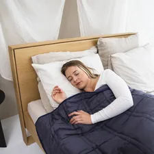 a woman laying in bed with a blue comforter related to Navy Quilted Coverlet: A Cozy Addition to Your Bedroom