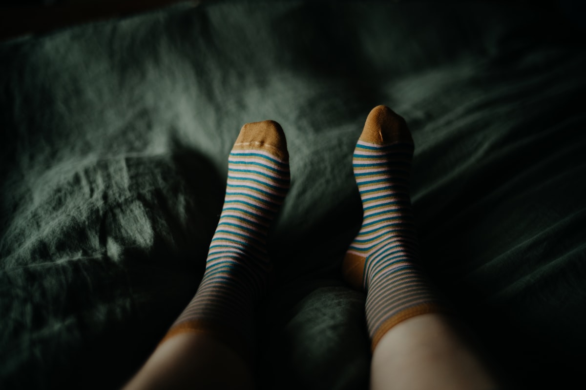 a woman's legs with blue and white striped socks related to Relieving Nocturnal Leg Discomfort: Why Legs Ache at Night in Bed