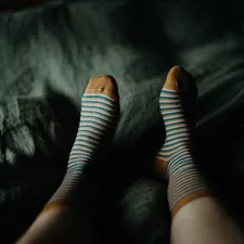 a woman's legs with blue and white striped socks related to Relieving Nocturnal Leg Discomfort: Why Legs Ache at Night in Bed
