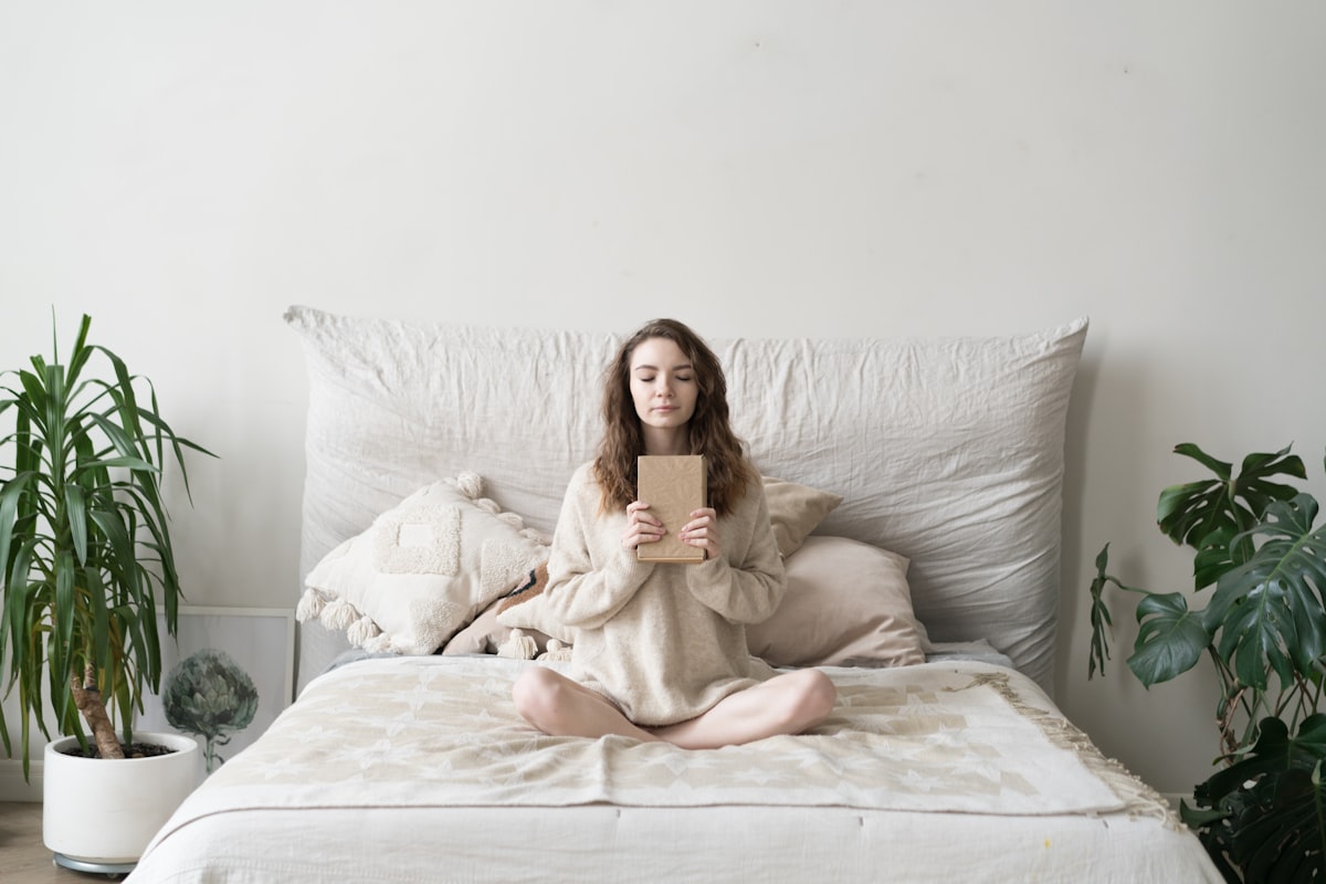 a woman sitting on a bed holding a tablet related to Elevate Your Bedtime Experience