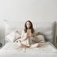 a woman sitting on a bed holding a tablet related to Elevate Your Bedtime Experience