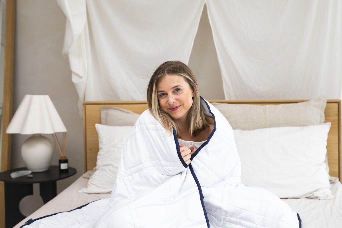 a woman sitting on a bed wrapped in a blanket related to Queen Size Coverlets