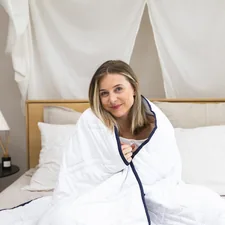 a woman sitting on a bed wrapped in a blanket related to Queen Size Coverlets