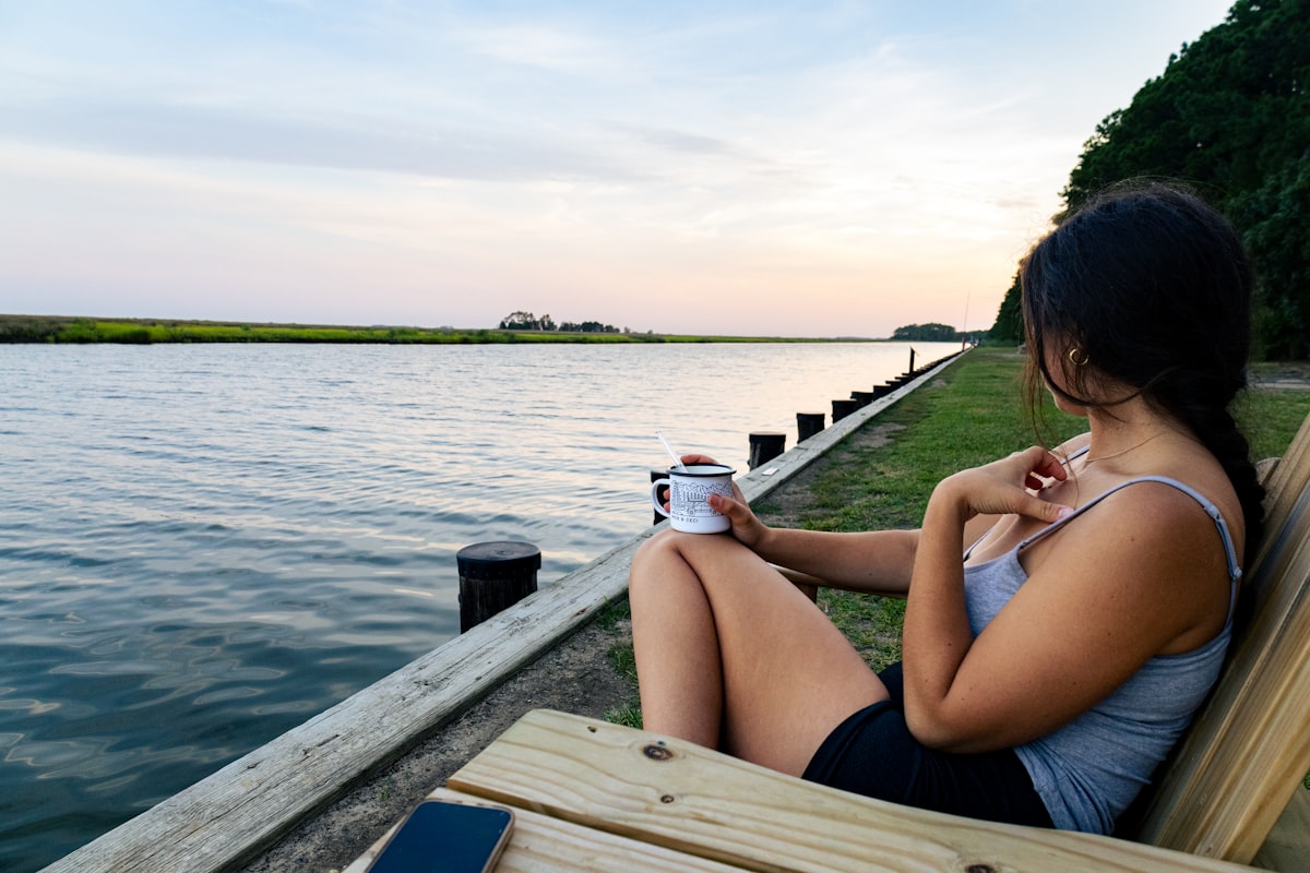A woman sitting on a bench next to a body of water related to Top Bed and Breakfasts in Maryland: Your Ultimate Guide to Cozy Stays