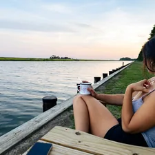 A woman sitting on a bench next to a body of water related to Top Bed and Breakfasts in Maryland: Your Ultimate Guide to Cozy Stays