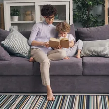 a woman sitting on a couch reading a book to a child related to Cozy Up to Savings: Sofa Bed Sale You Won't Want to Miss