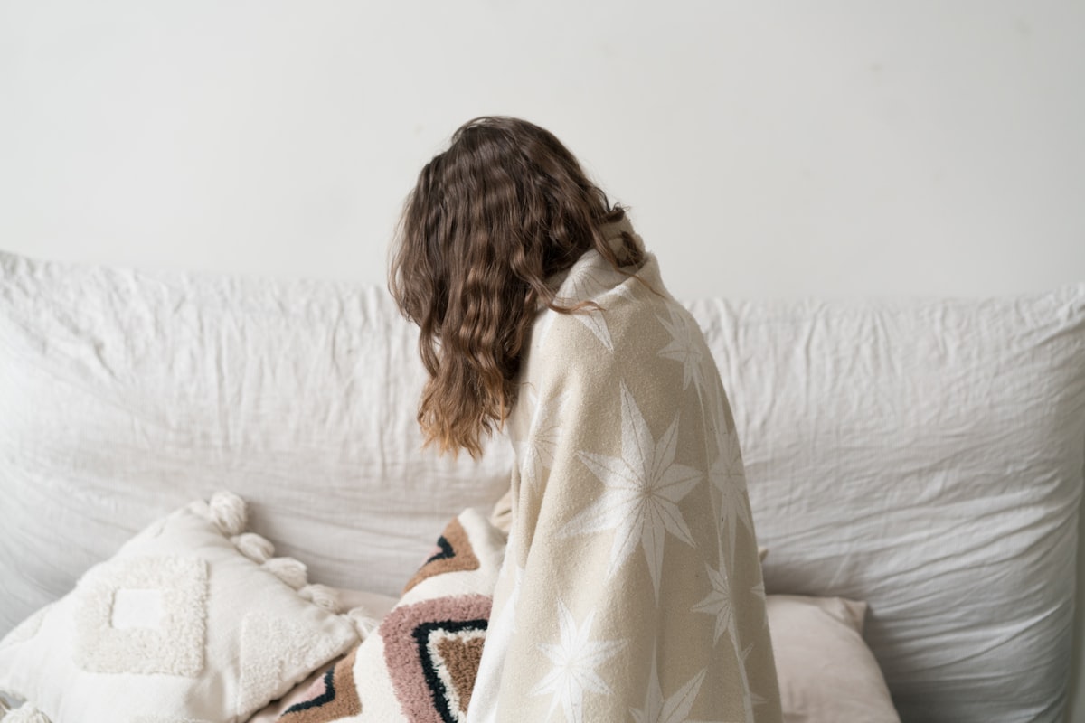 a woman sitting on a couch with a blanket related to Cozy Comfort for Little Dreamers: Explore the Best IKEA Children's Beds