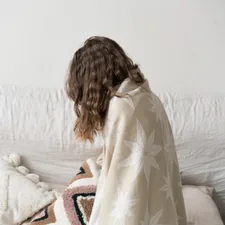 a woman sitting on a couch with a blanket related to Cozy Comfort for Little Dreamers: Explore the Best IKEA Children's Beds