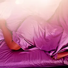 A woman sleeping on a bed with pink sheets related to The Ultimate Guide to Finding the Perfect Bed for Women