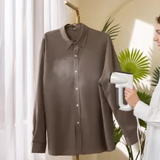 A woman smiles while steaming a taupe button-down shirt with Neakasa M1 vacuum steamer related to Effective Solutions for Bed Bug Treatment