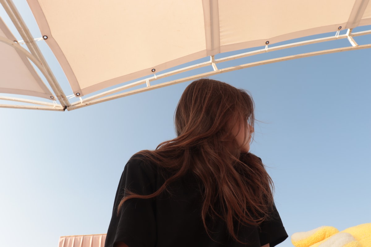 a woman standing under a white umbrella under a blue sky related to The Elegance of the Black King Canopy Bed: A Luxurious Addition to Your Bedroom