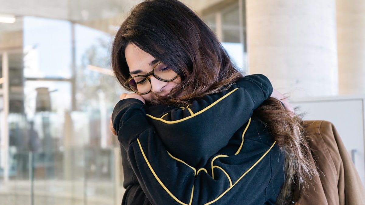 a woman with glasses is looking down at her phone related to Effortless Elegance: A Guide to Draping a Scarf Valance