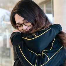 a woman with glasses is looking down at her phone related to Effortless Elegance: A Guide to Draping a Scarf Valance