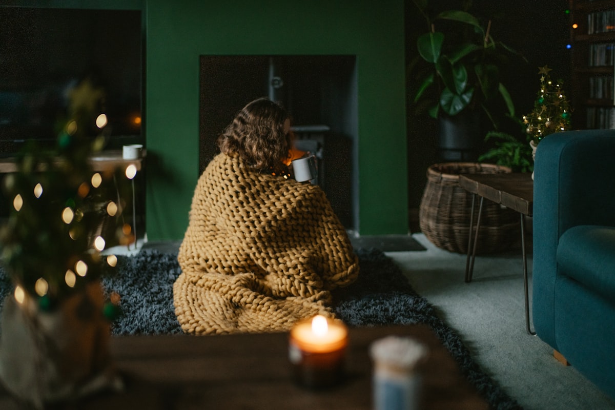 a woman wrapped in a blanket sitting on a rug in a living room related to Experience the Cozy Side of B&B: Groupon Deals