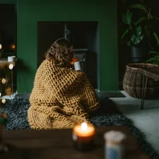 a woman wrapped in a blanket sitting on a rug in a living room related to Experience the Cozy Side of B&B: Groupon Deals