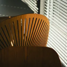 A wooden chair sitting in front of a window related to Wood Blinds: Reliable & Stylish Valance Clips for Perfect Window Coverings