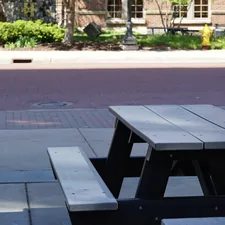 A wooden picnic table on a paved outdoor area. related to Safeguarding Your Outdoor Space: The Importance of Chiminea Spark Arrestors