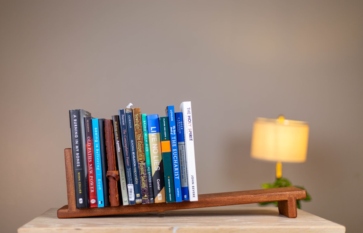 a wooden shelf with a lamp and books on it related to Maximizing Space: The Ultimate Guide to Over Bed Shelves