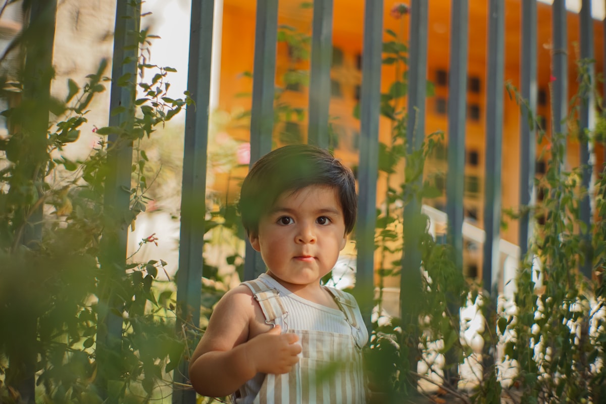 a young child standing in front of a fence related to Essential Guide to Choosing the Best Rail for Toddler Bed
