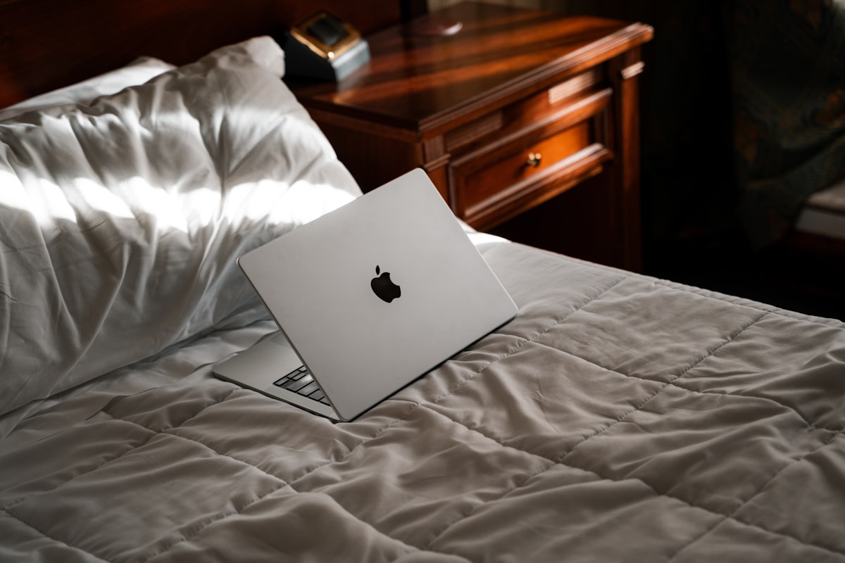 An apple laptop sitting on top of a bed related to Luxurious Satin Coverlets Bedspreads for a Stylish Bedroom