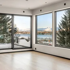 An empty room with large windows overlooking a lake related to Elevate Your Windows with Custom Valances