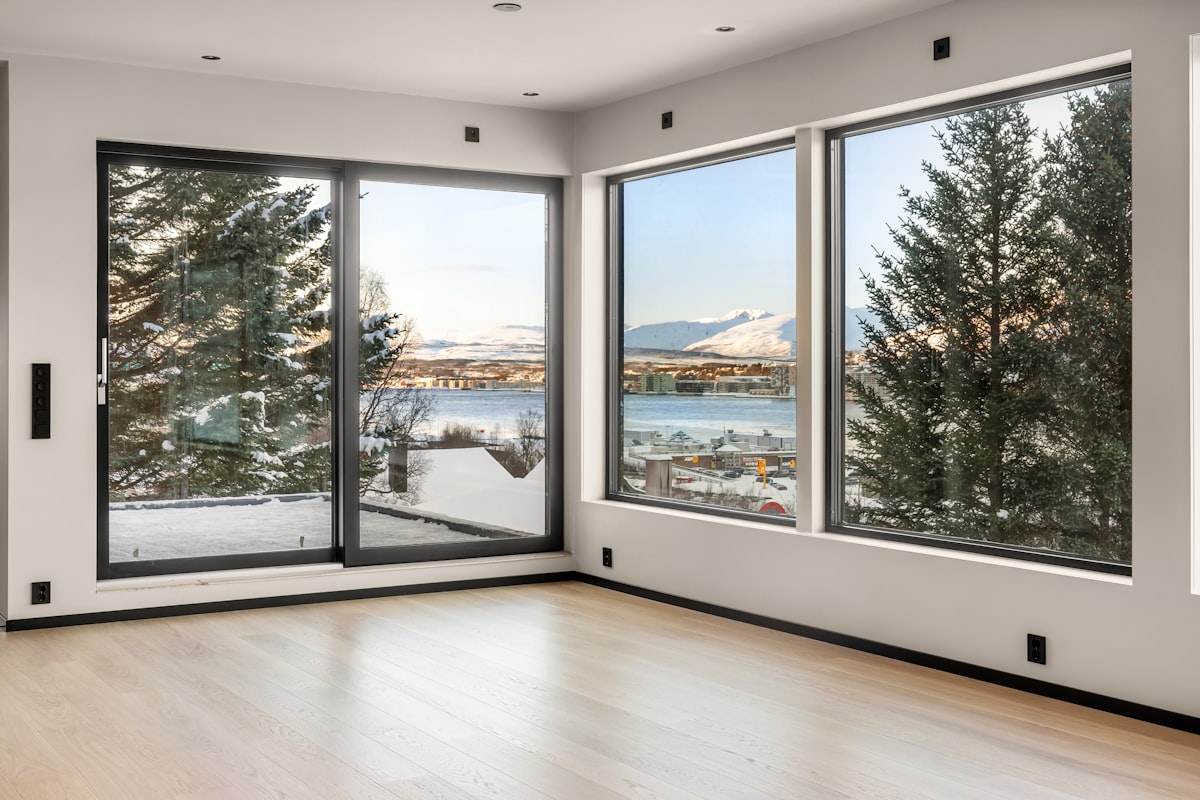 An empty room with large windows overlooking a lake related to Elevate Your Windows with Custom Wood Cornice Valance