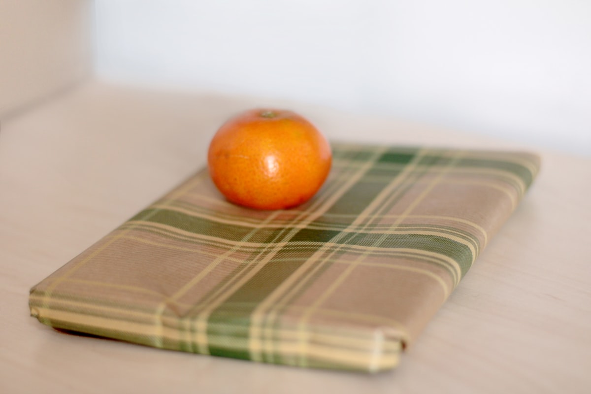 an orange sitting on top of a napkin on a table related to Full Size Coverlet