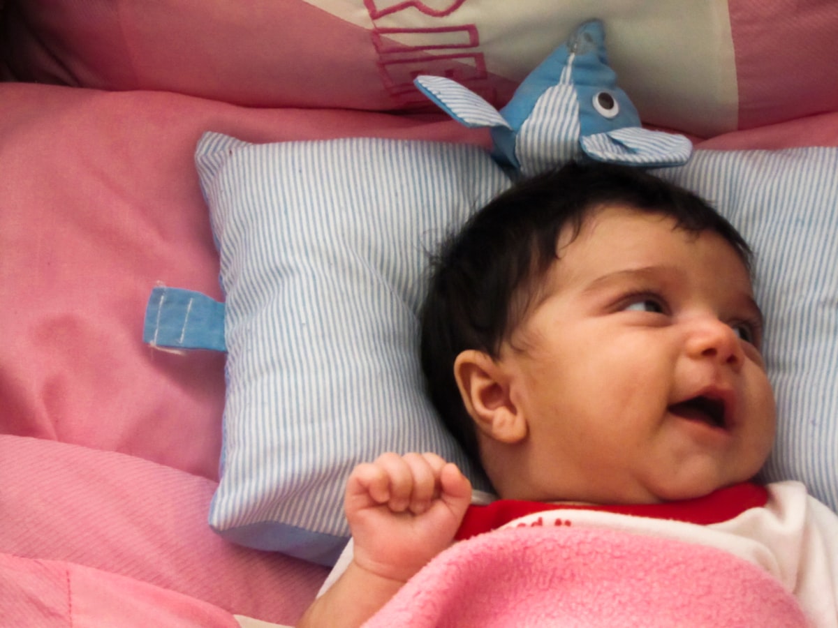 baby in pink shirt lying on bed related to Anchors Aweigh: Top Nautical Crib Bedding Sets for Your Little One