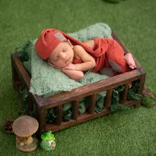 baby in red and white stripe onesie lying on brown wooden bed related to Snuggle and Snort: Creating a Cozy Nest for Your New Arrival