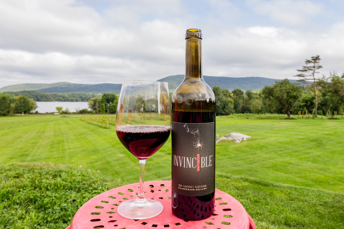 black and red labeled bottle beside wine glass on pink table mat related to Charming Escapes: Discovering the Best Berkshires Bed and Breakfasts