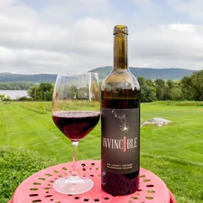 black and red labeled bottle beside wine glass on pink table mat related to Charming Escapes: Discovering the Best Berkshires Bed and Breakfasts