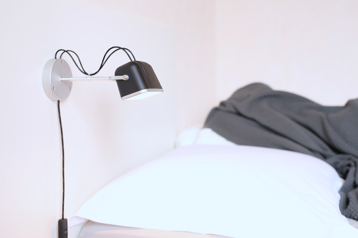 Black wall lamp next to white pillow related to Revolutionizing Your Hair Game: The Power of Bed Head Wavers