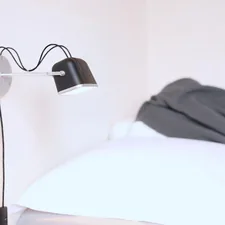 Black wall lamp next to white pillow related to Revolutionizing Your Hair Game: The Power of Bed Head Wavers