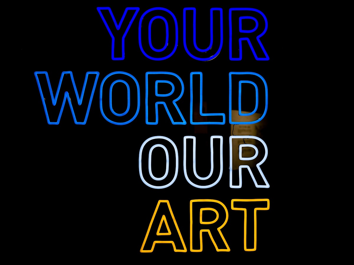 Blue and yellow neon sign that reads, “Your World sour Art” related to Add a Pop of Color to Your Windows with Bright Colored Valances