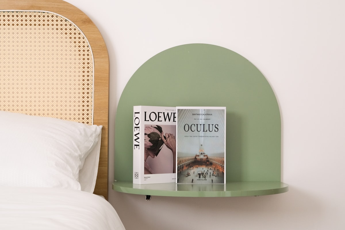 Books and decor on a stylish, green wall shelf. related to Maximizing Space: The Ultimate Guide to Over Bed Shelves
