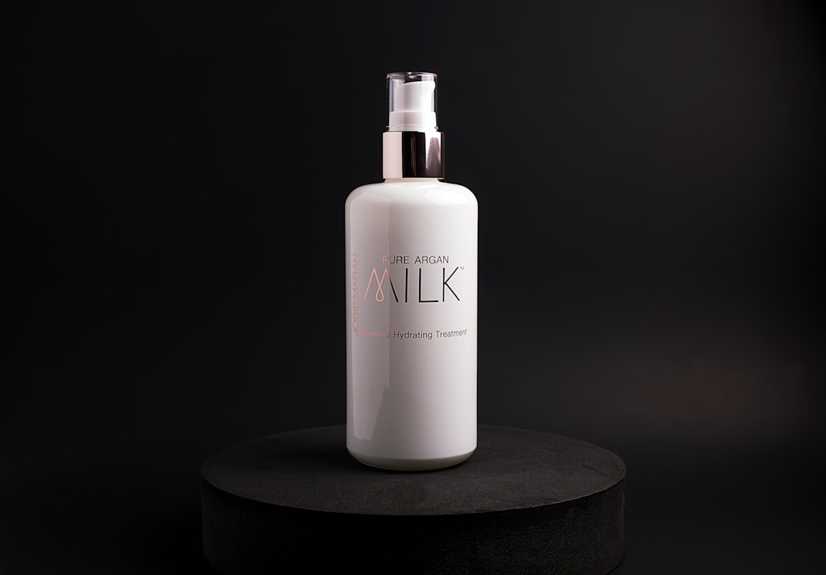 Bottle of Josie Maran Pure Argan Milk product photo shoot on black backdrop with black circle. related to Top Picks for Milk Frothers at Bed Bath & Beyond