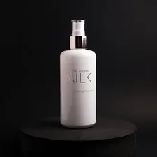 Bottle of Josie Maran Pure Argan Milk product photo shoot on black backdrop with black circle. related to Top Picks for Milk Frothers at Bed Bath & Beyond