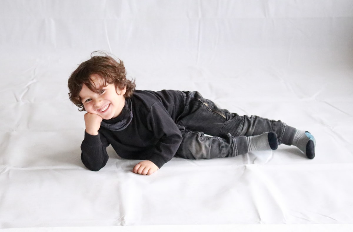 boy in black leather jacket lying on white bed related to Cotton Toddler Bedding: Soft and Cozy for Your Little One