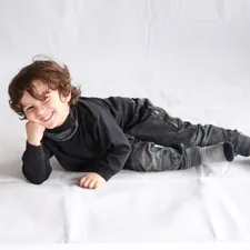 boy in black leather jacket lying on white bed related to Cotton Toddler Bedding: Soft and Cozy for Your Little One