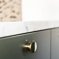 Brass knob on green kitchen front with marble countertop. related to Elevate Your Home Decor with a Marble Top Sideboard