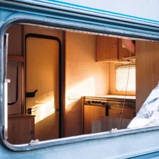 Broken window on a light blue caravan interior related to Choosing the Best Ladder for Your RV Bunk Bed