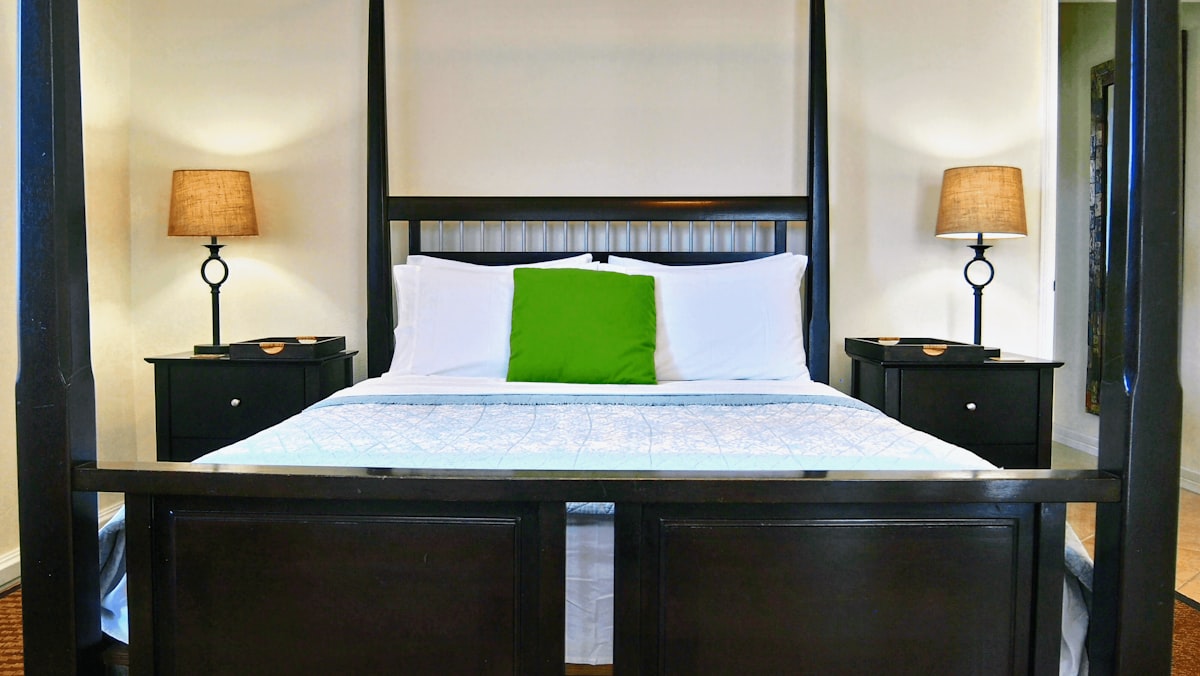 brown wooden bed frame with white and pink floral bed linen related to Elevate Your Sleep Experience with a King Size Canopy Bed