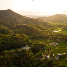 buildings on grass field near forest and mountains during day related to Exploring the Charm of Bed and Breakfasts in Tennessee