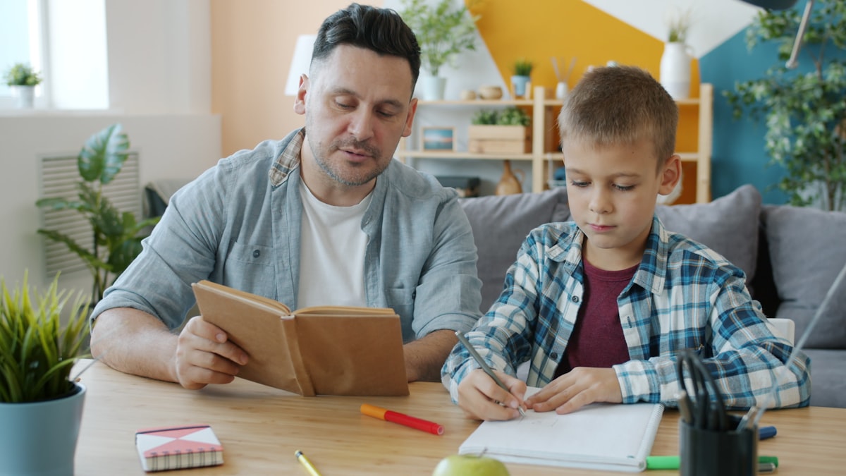 Caring dad is reading book to kid while child is drawing pictures at desk in apartment enjoying creative activity and leisure time with father. Culture and youth concept. related to Elevate Study Time: The Ultimate Guide to Kids Bunk Beds with Desk