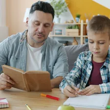 Caring dad is reading book to kid while child is drawing pictures at desk in apartment enjoying creative activity and leisure time with father. Culture and youth concept. related to Elevate Study Time: The Ultimate Guide to Kids Bunk Beds with Desk