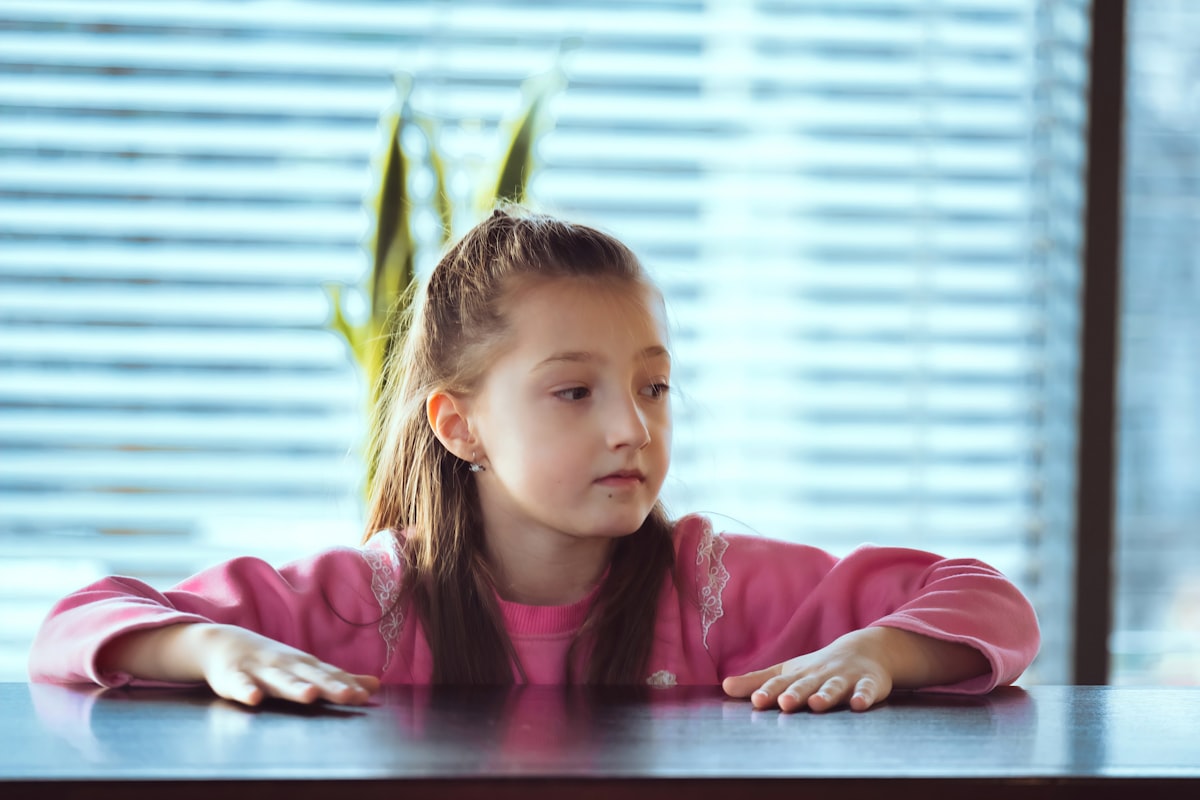 Child sitting on the table looking away to side. Portrait of a little girl in deep thought. related to Girls Window Valance Ideas and Options